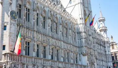 A detailed view of the Gothic-style Town Hall in Brussels with flags and intricate stonework. (stock photo via Pexels)