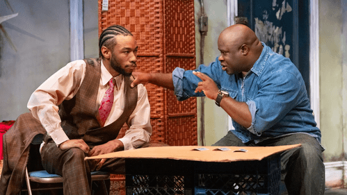 McGriff, in cornrows and a brown plaid suit, listens earnestly to Davis, in a denim shirt, gripping McGriff’s shoulder.