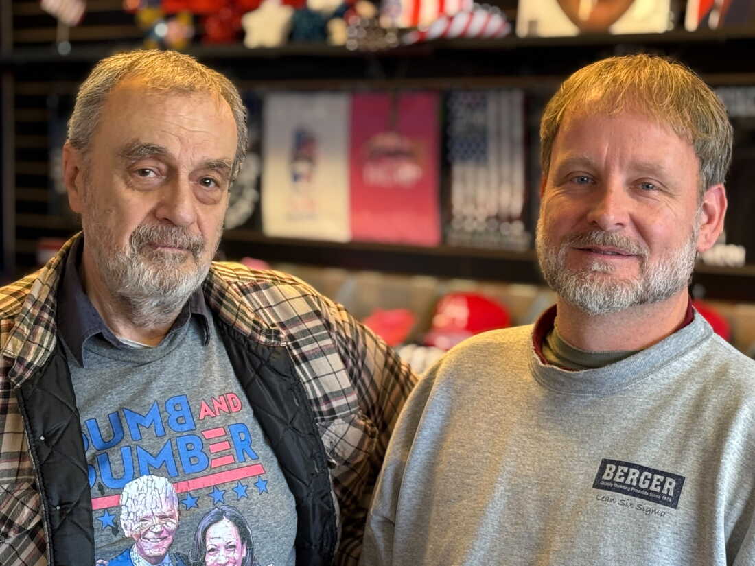 Two Trump fans pose amid merchandise at a Trump store that is closing
