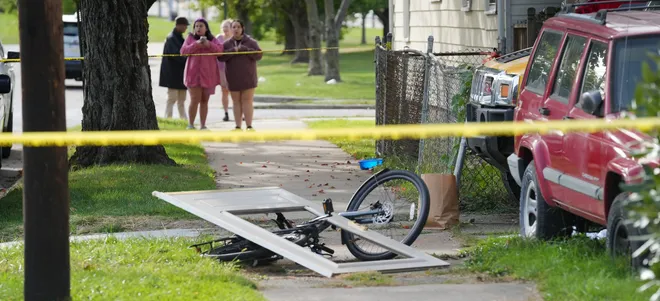 Bystanders gather near the site where nine people died in a reported shooting in and around a home at 722 Perry St. in Erie, Pa., Oct. 9, 2026. Erie Bureau of Police investigators were on the scene Oct. 10. Governor Shapiro offers Erie 'full support' in wake of mass shooting