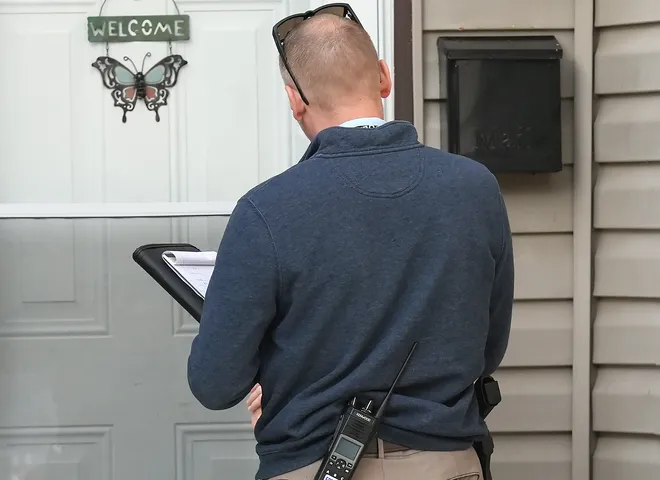 An Erie Bureau of Police investigator speaks with a neighbor near the scene where multiple people were killed in a reported shooting in and around a home at 722 Perry St. in Erie, Pa., Oct. 9, 2026. Erie police chief details timeline of deaths in mass shooting