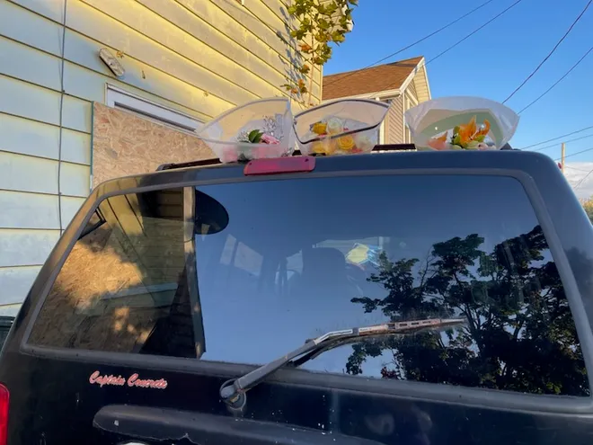Three bouquets of flowers are shown Oct. 13, 2026, placed on top of a vehicle parked outside of 722 Perry St. in Erie, Pa. This was the address where a mass shooting took place on Oct. 9.
