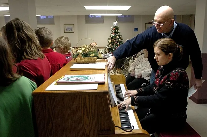 Tracy Elementary School Principal Denny Libra turns pages for music teacher Mary Dudenhoeffer in December 2007.