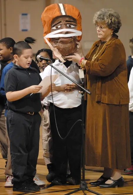 Wiley Charter School fourth-grade student Kane Giglio, 10, reads a biography of Jim Brown's life as his teacher, Johanna Morth, holds up a paper mache depiction of Brown during a tribute to Dr. Martin Luther King Jr. at the Boys and Girls Club of Erie County in Erie on Jan. 18, 2007. Students gave presentations after a march from Wiley Charter School to the Boys and Girls Club of Erie.