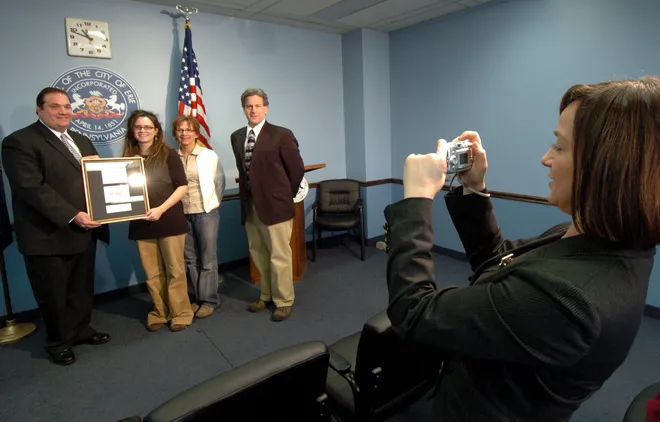 Jill Chiccarino Beck, administrative assistant, takes a photograph of Mayor Joe Sinnott, left, with Rachele Bowden, 17; her mother, Nancy Bowden; and Jim Rinderle, art teacher at Northwest Pennsylvania Collegiate Academy, in January 2008. Rachele, a senior at Collegiate Academy, was recognized by the mayor for designing a Christmas Card for the City of Erie.