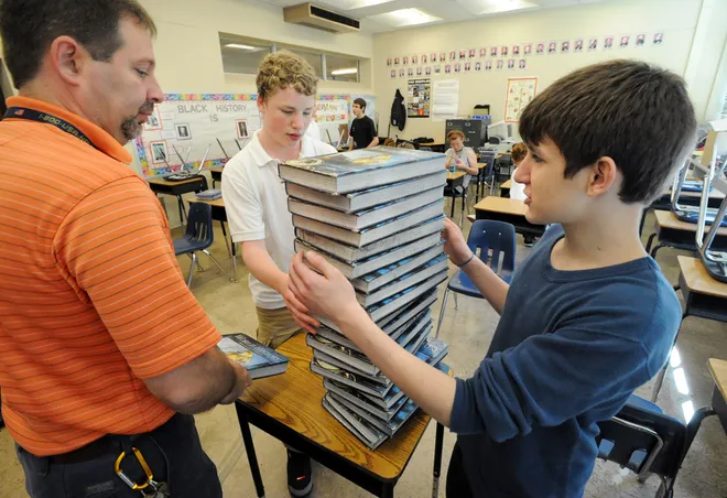 Central Tech High School teacher Greg Holland, left, gets help putting books away from students Luke Manges, center, and Richard Decker, both 15, at the school on June 6, 2008.