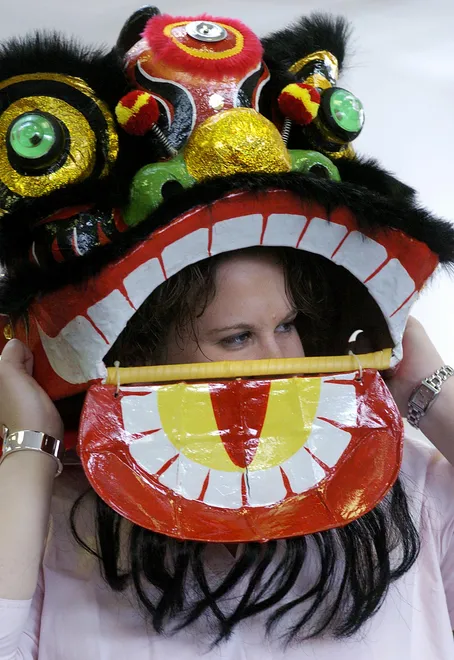 Our Lady's Christian School first-grade teacher Amy Bauschard, wearing a dragon mask, leads a group of first- and second-grade students around the library as they celebrate Chinese New Year at the Millcreek Township school on Feb. 11, 2010.