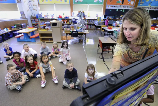 Kindergarten teacher Marci Stitt, right, explains an assignment to her students at Glenwood Elementary School in Erie on Sept. 25, 2009.