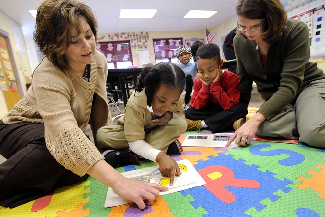 From left, McKinley Elementary School reading teacher Kimberly Fachetti reads along with kindergartner Amari Jordan, 5, while first-grader Bashan Stewart, 6, reads with reading teacher Gretchen Cunningham in Erie on Dec. 22, 2009.