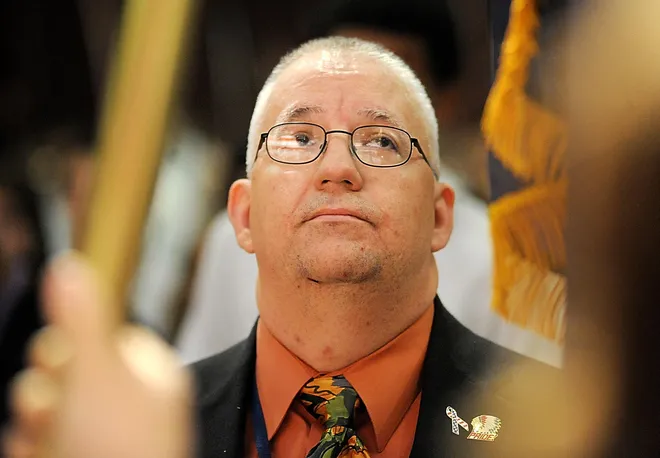East High School teacher John Boyko gazes up at the American flag as the national anthem is performed by student Shanequa Quinn on Nov. 2, 2009. The school officially welcomed Boyko back to the school after he had served for the previous year in Iraq.