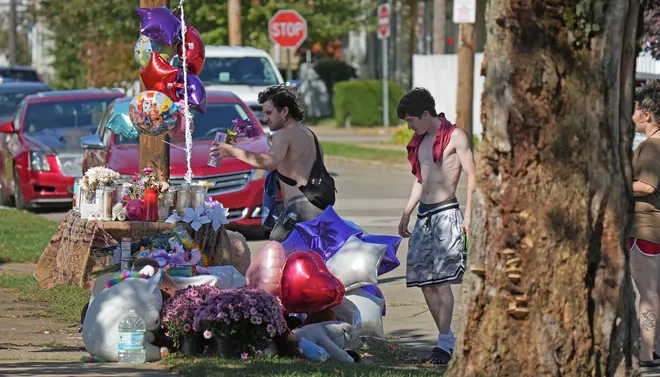 Passers-by replace candles blown over by winds at the memorial for victims of a mass shooting at 722 Perry St. in Erie, Pa., Oct. 13, 2026. The shooting took place on Oct. 9.