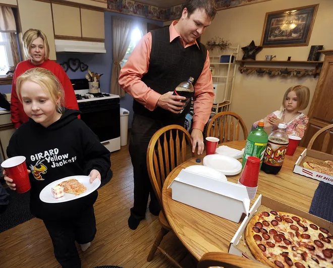 Elk Valley Elementary School Principal Mike Trudnowski, at top center, gets a soda at the Moore home in Lake City on April 19, 2010. Alyssa Moore, 9, at front left, Paige Moore, 6, at right, and Chris Moore, at back left, get ready to eat the pizza that Trudnowski brought over during a visit to their home. Trudnowski, as well as the vice principal and teachers, made house calls to parents, taking books and pizza, in order to build better home-school rapport.