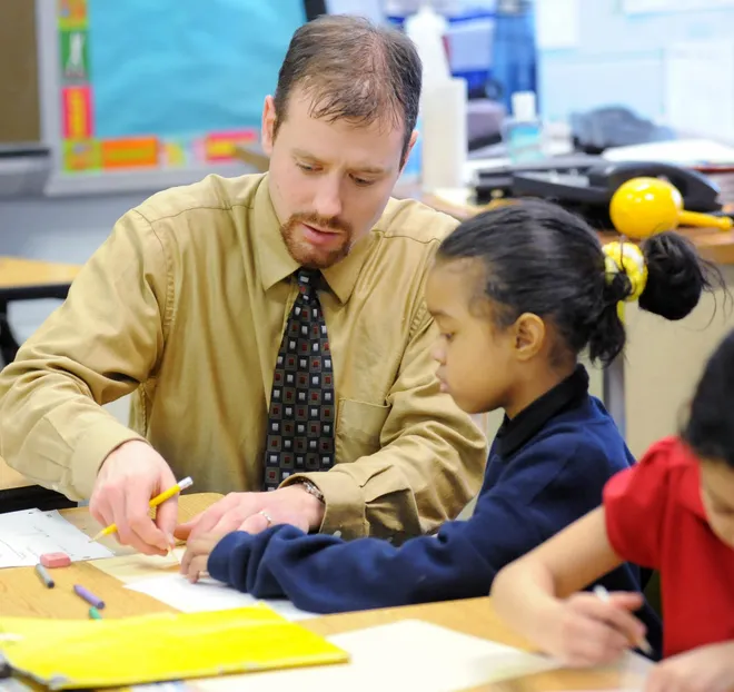 Art teacher Kevin Slagle, left, works with Reonica Valadez, a first-grade student at Pfeiffer-Burleigh Elementary School, in Erie, on Feb. 2, 2011.