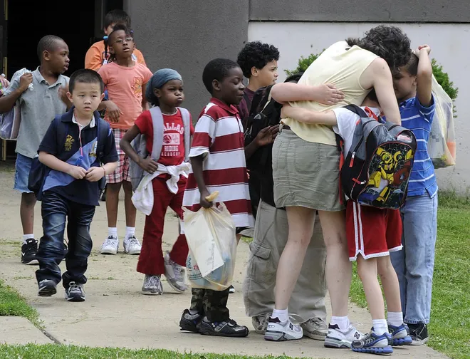 First-grade teacher Carrie BonGiorno gets hugs from her students as they leave Irving Elementary School on Erie's west side on June 9, 2011, the last day of the school year for the Erie School District.