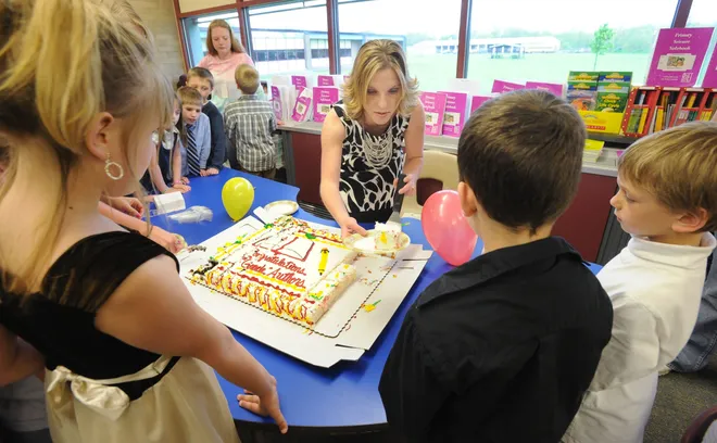 Nicole Drayer, a teacher at Elk Valley Elementary School, in Lake City, center, handles the cake detail for her first-grade class May 16, 2011. The students showcased the books they designed and threw a party celebrating the project and invited their parents and school board members. Children in the foreground are, from left, Anna Skinner, Cody Sterrett and Gavin Herman, all 7 and Girard residents.