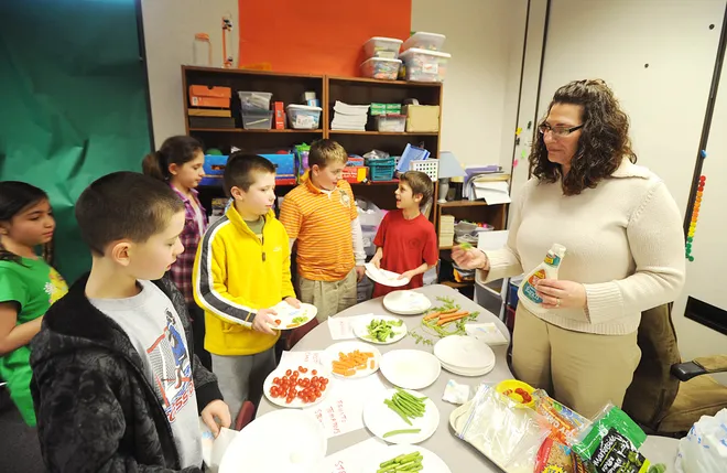 Tracy Elementary fourth-grade teacher Dana Gross on April 4, 2011, lets her students sample the kind of vegetables they were going to grow behind the school.
