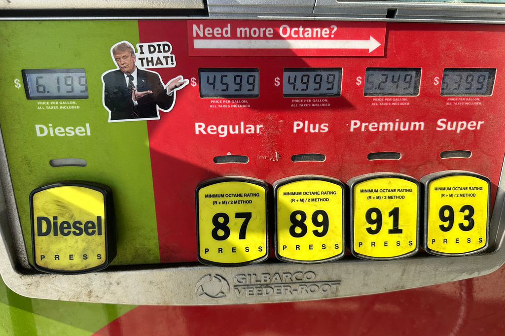 A gas pump display showing prices for Diesel, Regular, Plus, Premium, and Super, with a sticker of Donald Trump pointing to the Regular price.