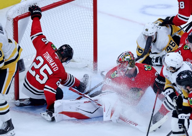 Chicago Blackhawks Dominic Toninato (25) hangs onto the top of the goal as goaltender Spencer Knight is unable to prevent Pittsburgh Penguins left wing Nick Robertson from scoring a goal in the second period of a game at the United Center in Chicago on Oct. 13, 2026. (Chris Sweda/Chicago Tribune)