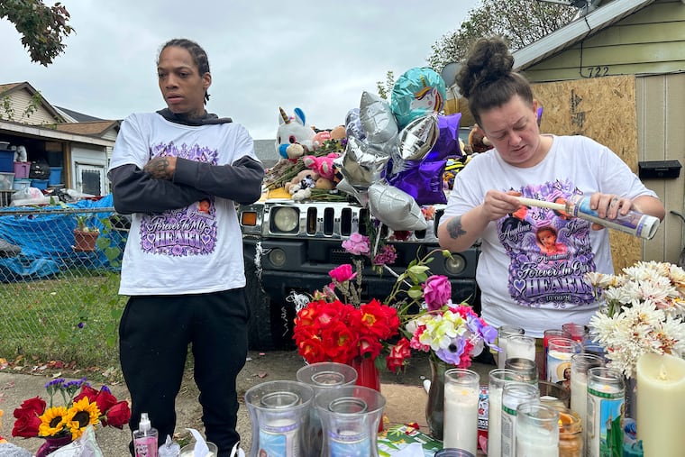 Julius Windham (left) visits a memorial outside the home where authorities say a gunman killed multiple people, including Windham's daughter, in Erie, Pa., on Sunday.