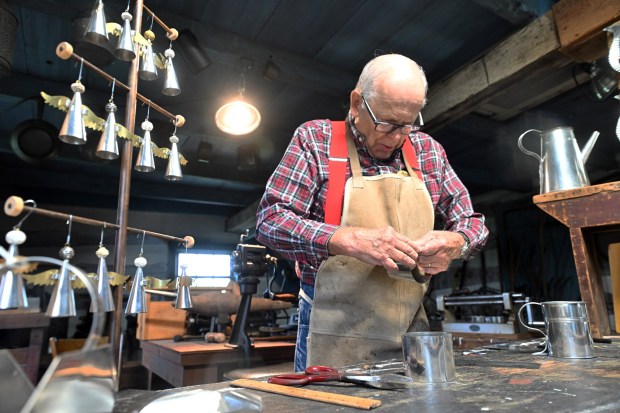 Tinsmith Ray Oxenford of Douglassville creates a tin cup at the shop in the former 1750 Thompson cabin that was relocated from Exeter Township during the Heemet Fescht at the Pennsylvania German Cultural Heritage Center at Kutztown University on Saturday, Sept. 26, 2026. (BILL UHRICH/READING EAGLE)