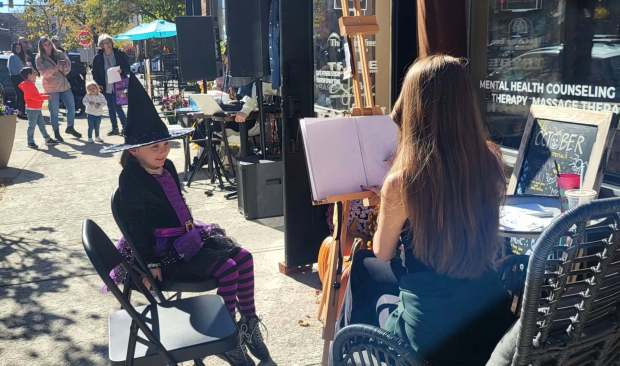 Ellie Price, 6, sits for her caricature on Saturday, Oct. 24, 2026, at the Giving Tree in downtown Scranton. The business also offered a DJ, face painting, pop-up shops and fall coffee specials as part of a downtown Fall Festival event. (GERI GIBBONS/STAFF PHOTO)