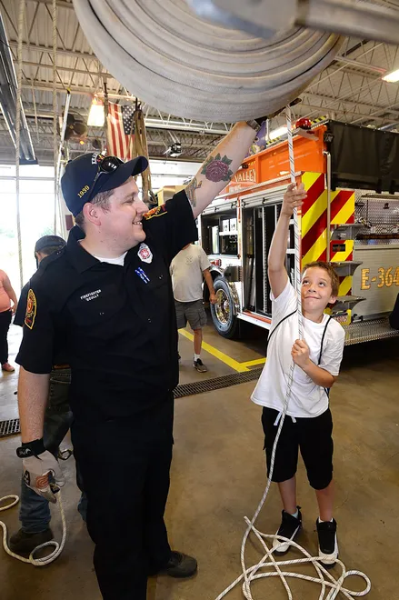 Kearsarge firefighter Kyle Scully shows Ivan Lamberty, 10, of Erie, how to use a haul system during the National Night Out event Aug. 2, 2017, at Belle Valley Fire Department in Millcreek Township. [JACK HANRAHAN/ERIE TIMES-NEWS]