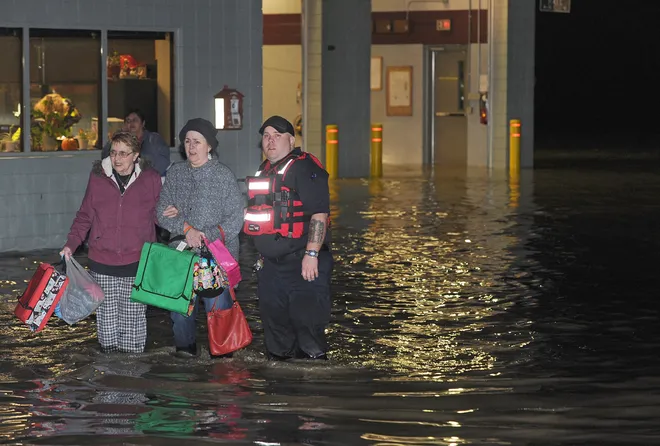 From left: Jean Schweitzer, 79, of Erie, and her daughter Betsy Yochim, 55, of Harborcreek Township, are helped out of the Belle Valley Fire Department on Nov. 5, 2017 by Chris Parker of the Millcreek Paramedic Service following severe flooding in the area. About 100 people who were playing bingo at Belle Valley were rescued. No injuries were reported. [CHRISTOPHER MILLETTE/ERIE TIMES-NEWS]
