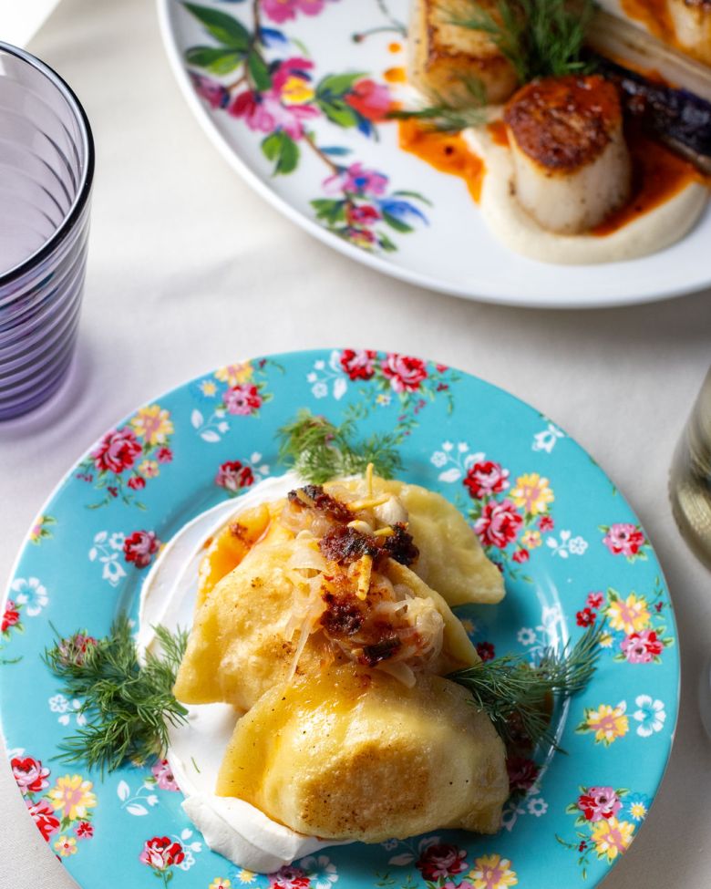 Pierogies with dill and sour cream on a blue floral patterned plate from Lilith.