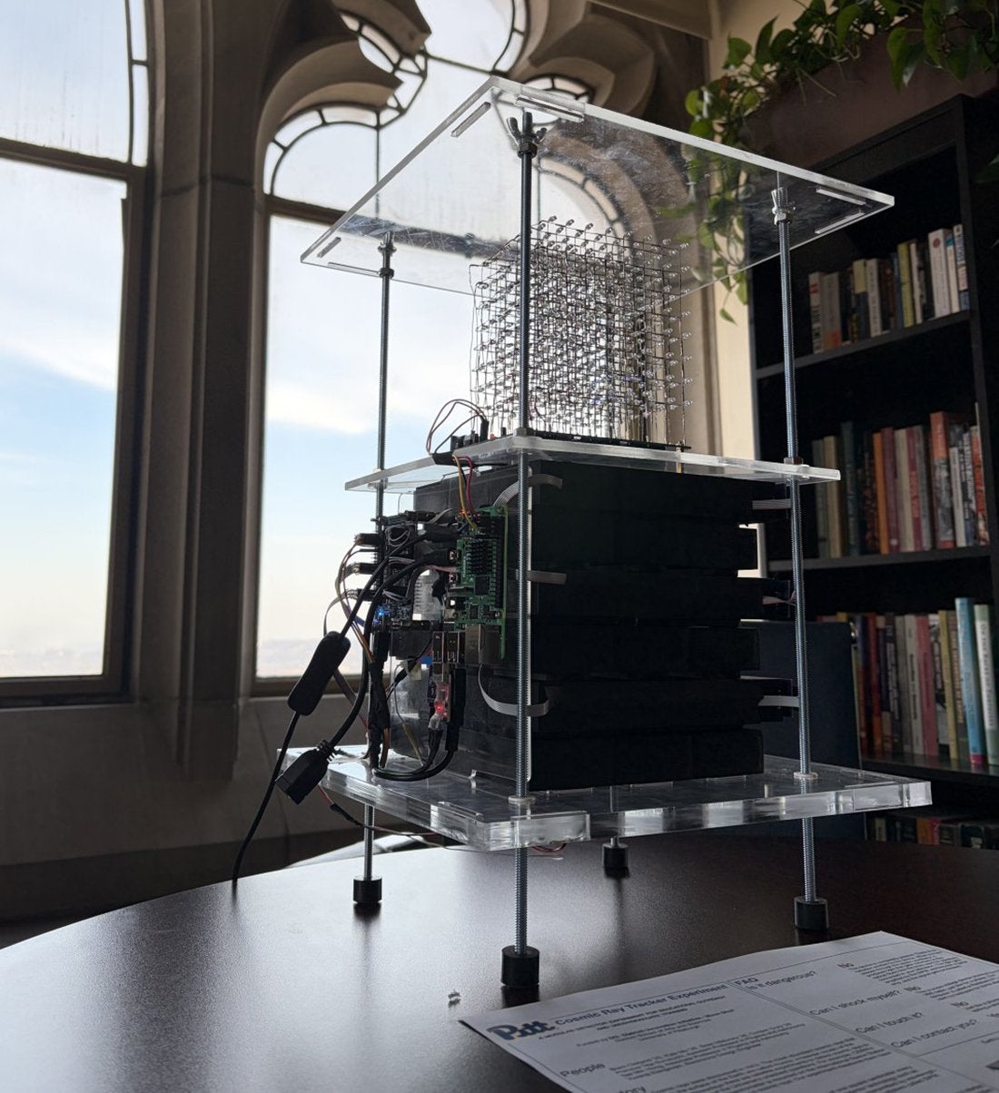 A cosmic ray device sits on a table in front of a window