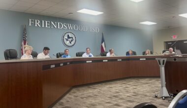 people sit behind a dais desk