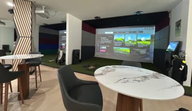 High tables and chairs next to a golf simulator bay.