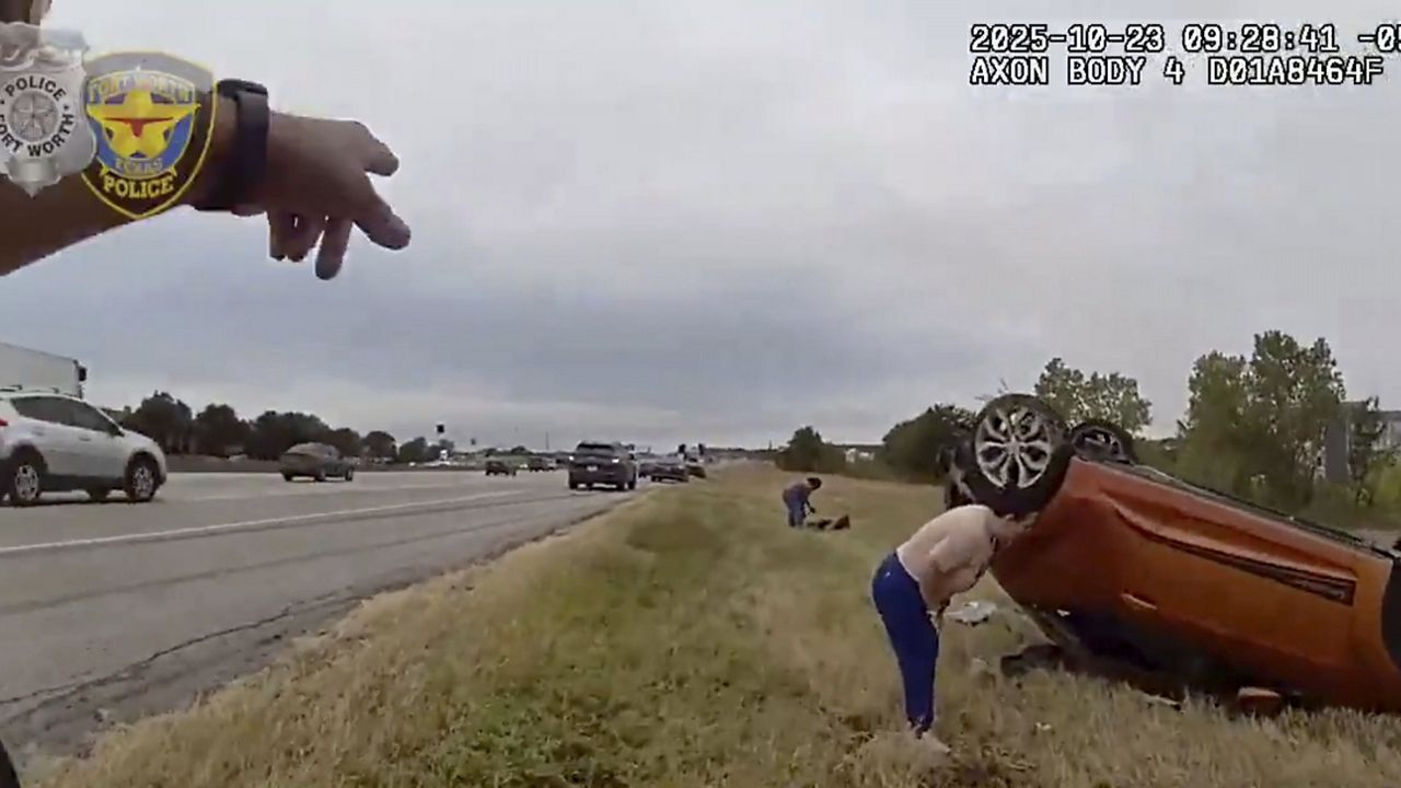 This image taken from video released by the Fort Worth Police Department shows officers responding to an overturned car before pulling a baby out from underneath Thursday, Oct. 23, 2025, in Fort Worth, Texas. (Fort Worth Police Department via AP)