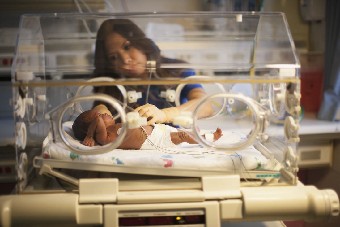 Nurse tending to newborn in incubator