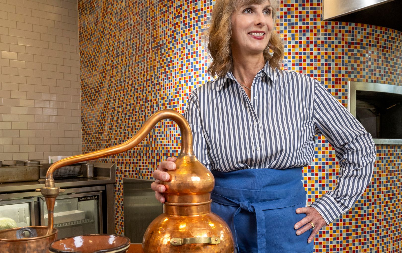 Amy Tigner stands with a copper still used to make chocolate and a traditional chocolate pot" style=" height:1020px; width:1620px" _languageinserted="true" src="https://cdn.prod.web.uta.edu/-/media/project/website/news/releases/2025/10/tigner.jpg