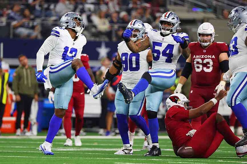 Dallas Cowboys' Dante Fowler Jr. (13) and Sam Williams (54) celebrate after sacking Arizona Cardinals' Jacoby Brissett, bottom right, in the second half of an NFL football game Monday, Nov. 3, 2025, in Arlington, Texas. (AP Photo/Richard Rodriguez)
