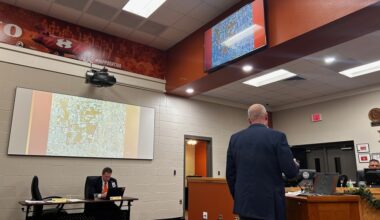a man at a podium speaking at a board meeting
