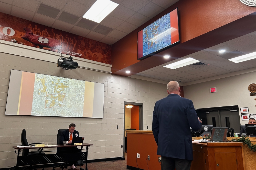 a man at a podium speaking at a board meeting