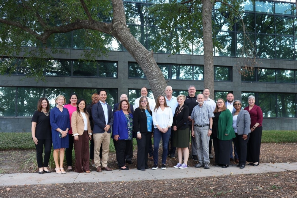 group of people stand in front of trees