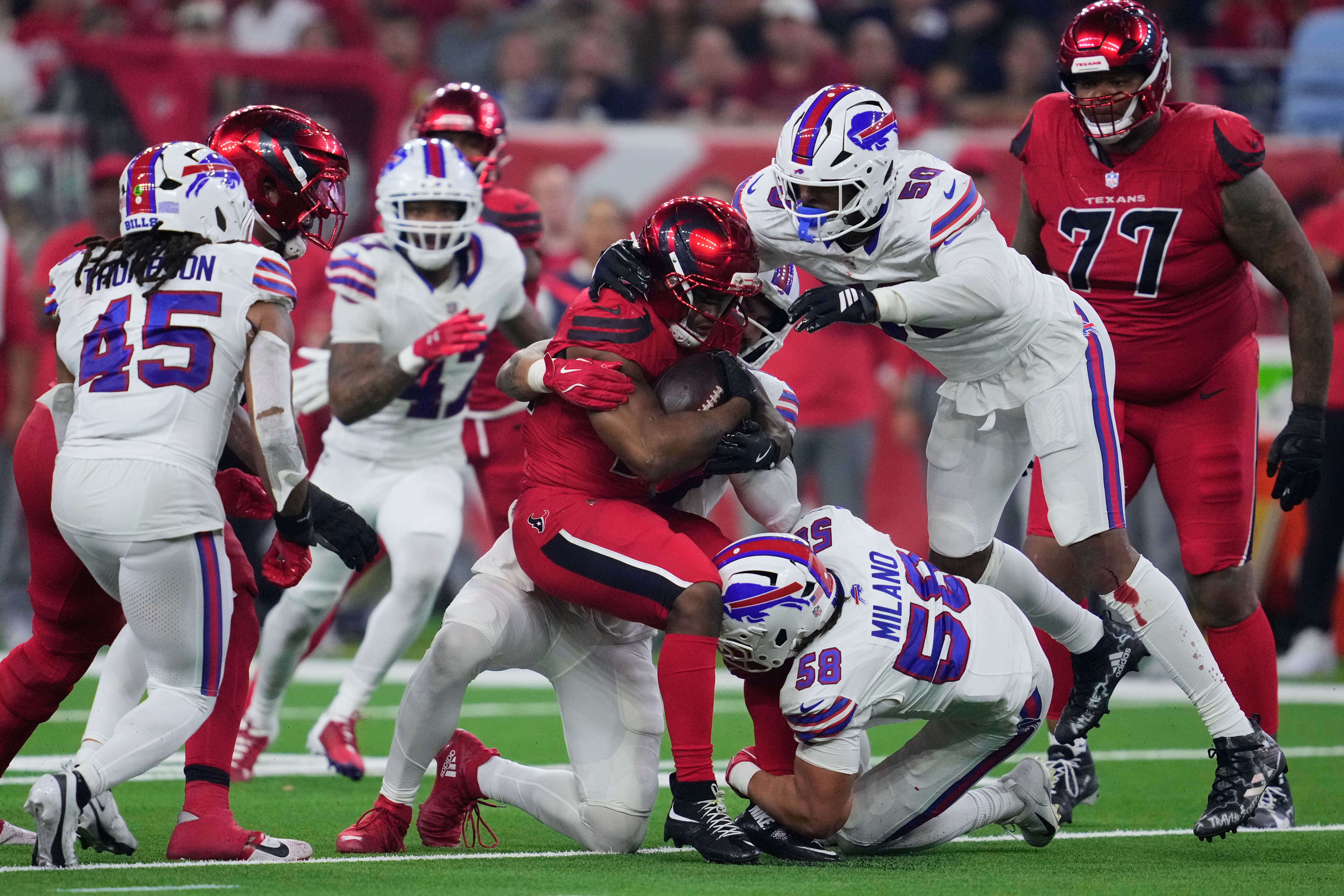 Houston Texans running back Nick Chubb, center, runs the ball as Buffalo Bills' Shaq Thompson (45), Matt Milano (58) and Greg Rousseau (50) combine to make the stop in the second half of an NFL football game Thursday, Nov. 20, 2025, in Houston. (AP Photo/Ashley Landis)