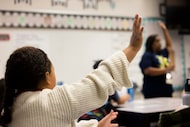 Students raise their hands as third grade teacher Anjelica Turner teaches about character...