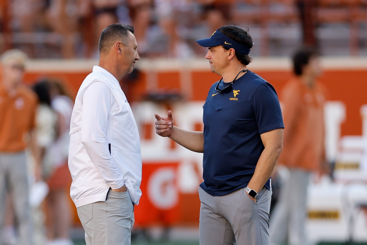 College football head coach Steve Sarkisian of the Texas Longhorns talks with head coach Neal Brown of the West Virginia Mountaineers
