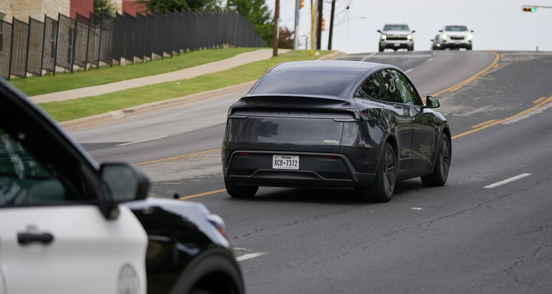 FILE — An Austin police car follows a driverless Tesla robotaxi in early July in Austin. Federal data show the company’s vehicles were involved in four crashes in the city during September.