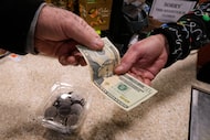 A shopper pays with cash for a container of candy at a store, Thursday, Dec. 11, 2025, in...