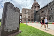 Visitors walk past a monument of the Ten Commandments outside the Capitol, Thursday, June...