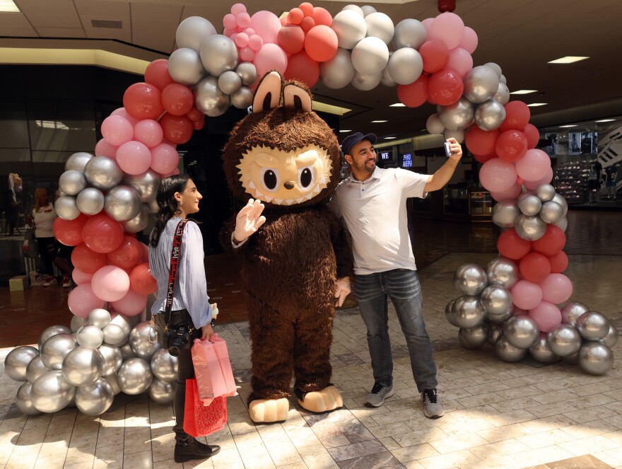 Aladeen Alhayek, right, takes a photo on his smartphone of himself and Amira Alhayek as they pose with a costumed labubu doll at the Labubu festival which was held at The Shops at RedBird in Dallas, on September 7, 2025.