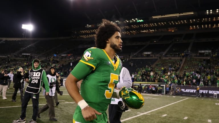 Oregon quarterback Dante Moore (5) runs off of the field...