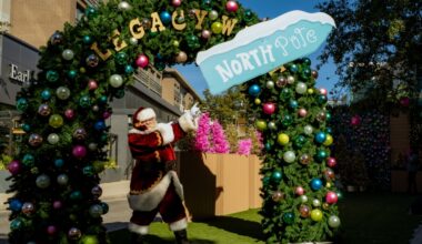 Santa Claus pointing at a North Pole sign