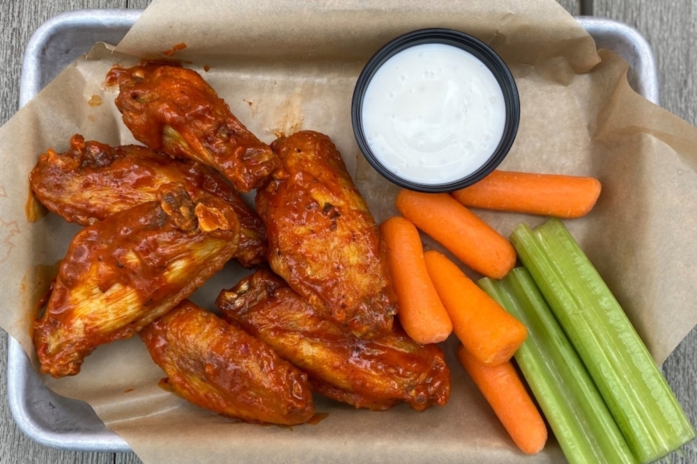 A plate of chicken wings, ranch, carrots and celery