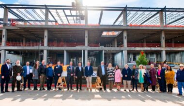 a group of people stand in front of a new college building that is under construction