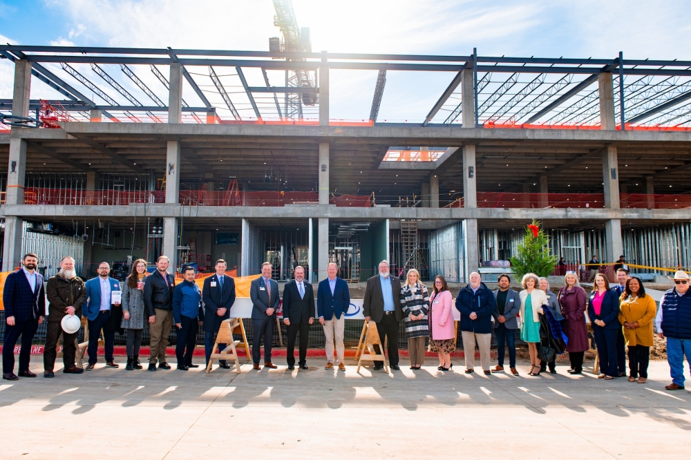 a group of people stand in front of a new college building that is under construction